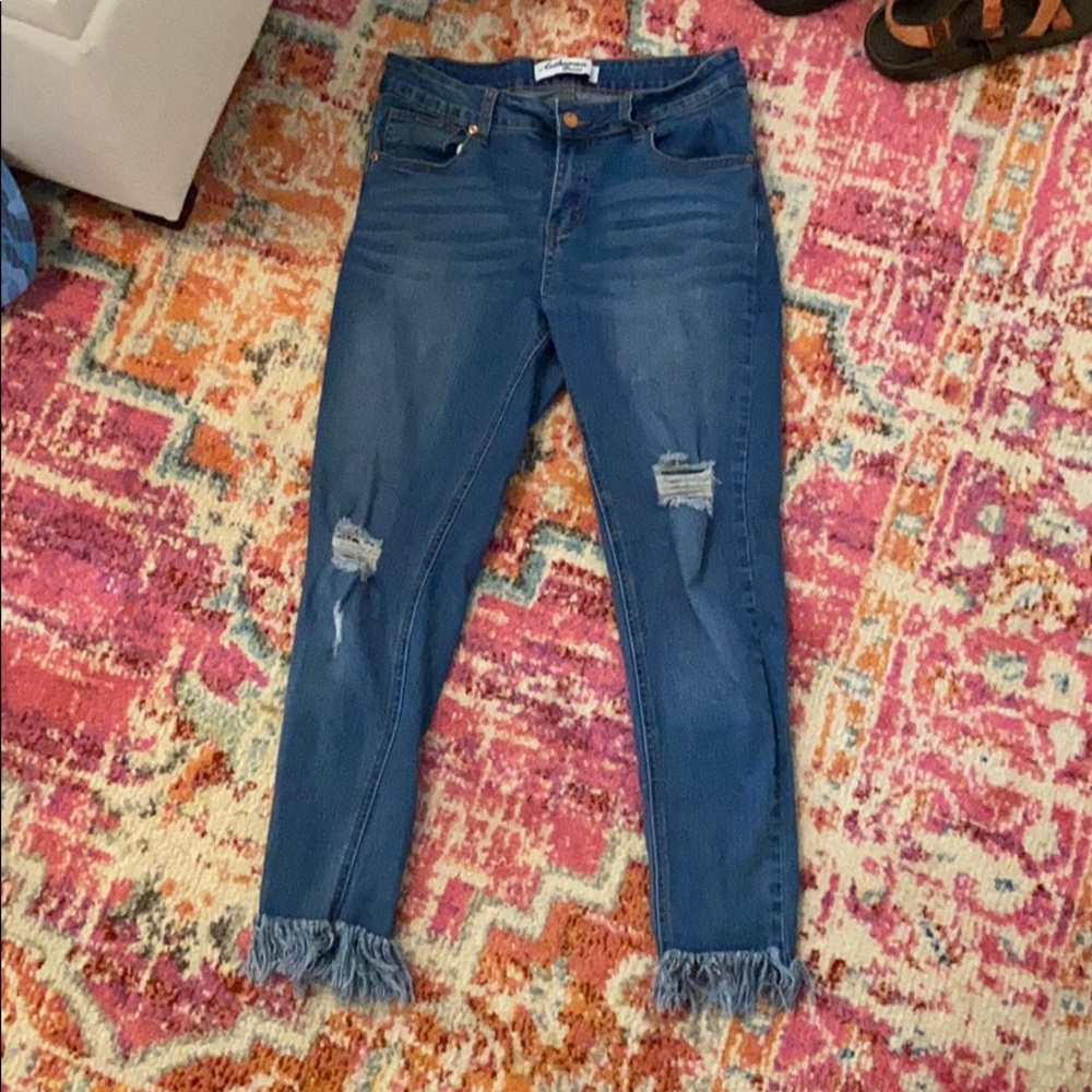 Blue jeans with decorative holes and frayed ankles